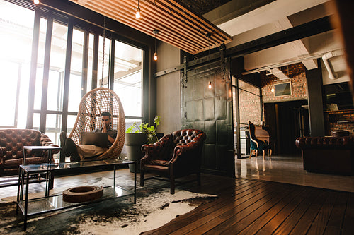 Business man relaxing in office lounge with laptop and thinking