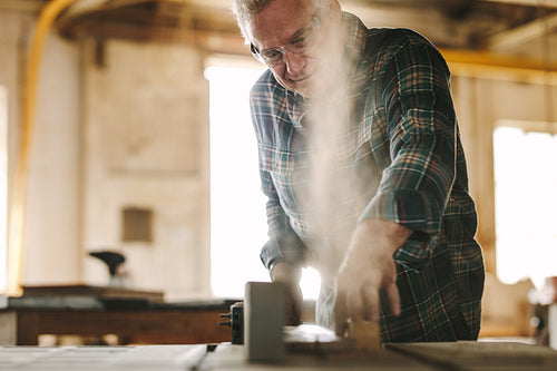 Senior carpenter cutting wood on table saw machine