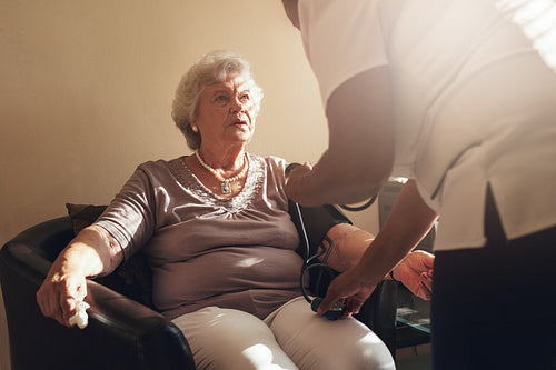Nurse measuring blood pressure of her senior patient