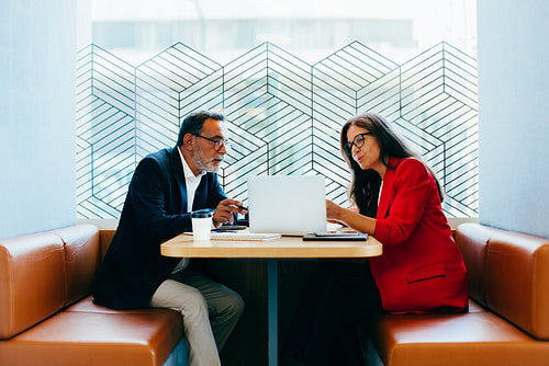 Two senior professionals discussing ideas during a meeting at a cafe table