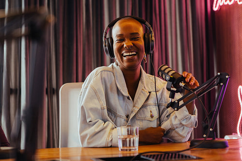 Joyful female radio presenter recording in studio with professional equipment