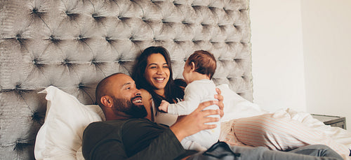 Happy parents playing with their newborn son on bed