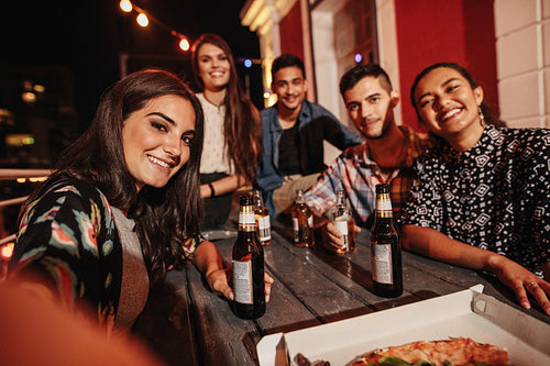 Woman taking selfie with friends at rooftop party