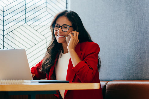 Confident businesswoman speaking on phone while working on her laptop