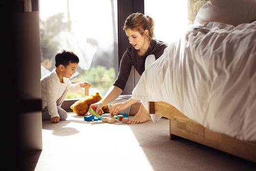 Little boy playing toys with his mother at home