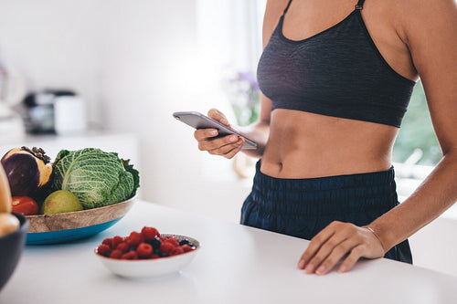 Young woman using mobile phone in kitchen