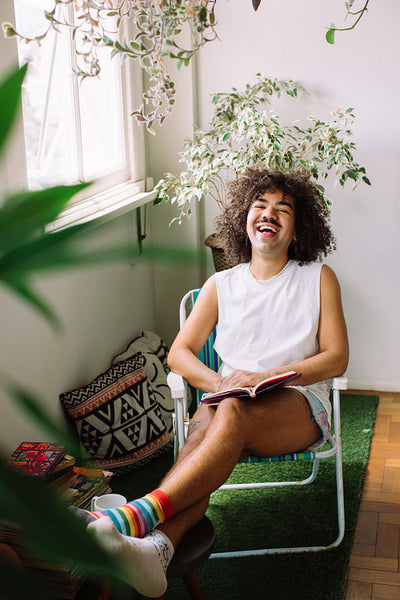 Cheerful gay man sitting with a book at home