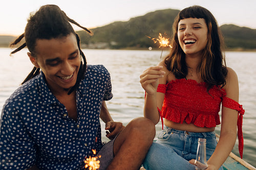 Cheerful young couple playing with Bengal lights on a vacation