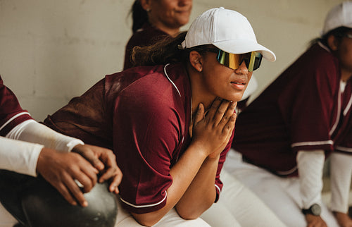 Focused female baseball player pondering game strategy and teamwork