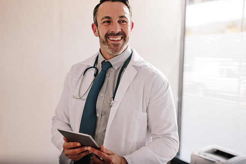 Mature male doctor with a digital tablet in his office