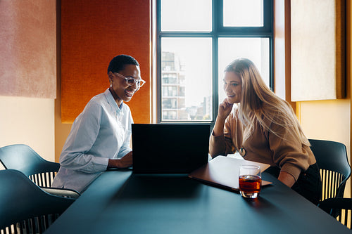 Two women discussing work at a modern office table
