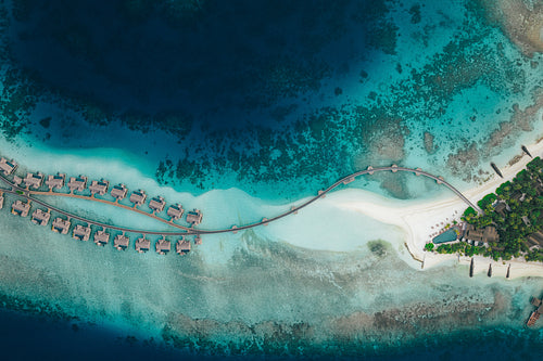 Tropical coast with sandy beaches, resort water villas, and vibrant coral reefs