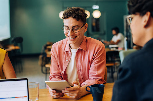 Smiling young man using a tablet while seated in a casual workspace