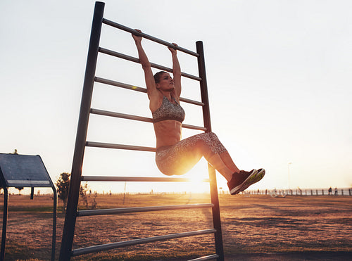 Fitness woman exercising on wall bars outdoors