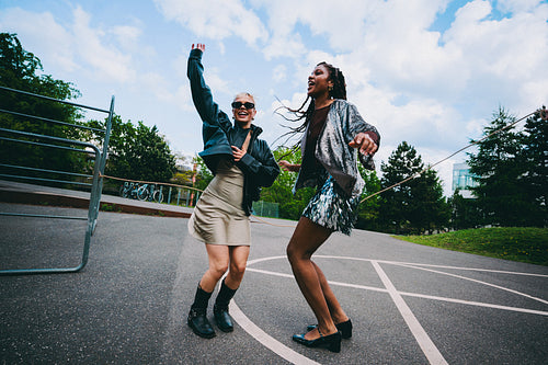 Young women jump rope and laugh outdoors