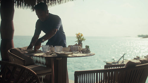 Waiter arranging elegant breakfast setup at oceanfront villa in the Maldives
