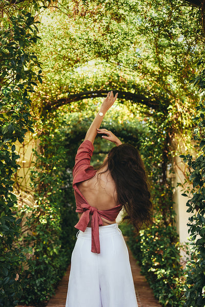 Glamorous young woman standing with her arms raised outdoors