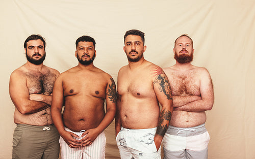 Men standing together in a studio without shirts