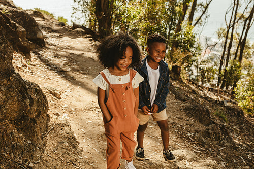 Cute boy and girl walking on a mountain trail