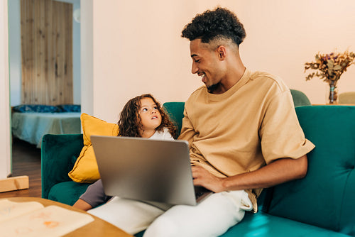 Happy single father using a laptop with his daughter at home