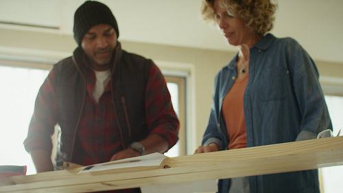 Man and woman discuss home renovation plans over blueprints