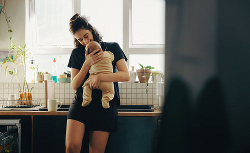 Mother holding baby in kitchen by window
