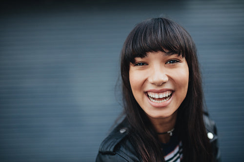 Young woman laughing against gray background