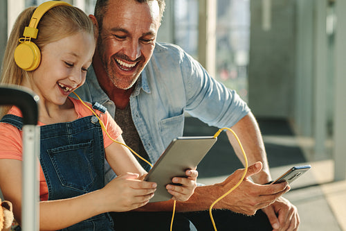 Family waiting at airport lounge using digital tablet