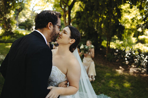 Bride and groom sharing a tender moment outdoors in a lush garden setting