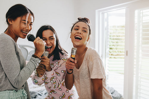 Happy girls singing karaoke during a sleepover