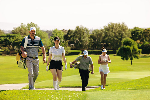 Group of golfers with golf bags walking on a golf course during a match