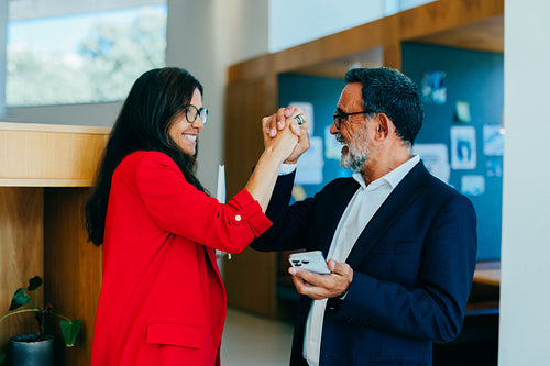 Senior colleagues high-fiving in the office sharing a moment of success