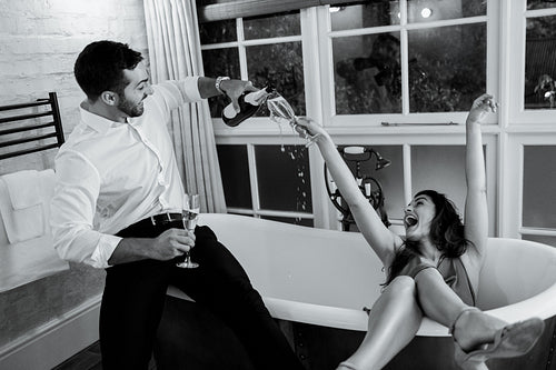 Lovely young couple having fun with champagne in a hotel bathroo