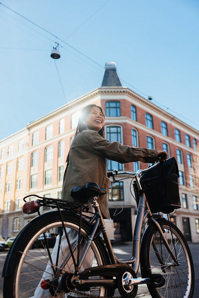 Woman smiling while commuting with her bicycle on a sunny day