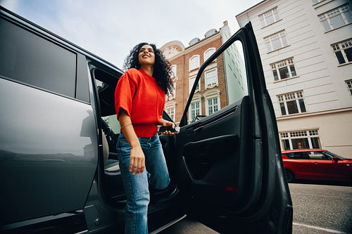 Woman exiting car on city street during daytime commute