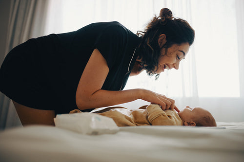 Mother tilts over baby smiling and playing