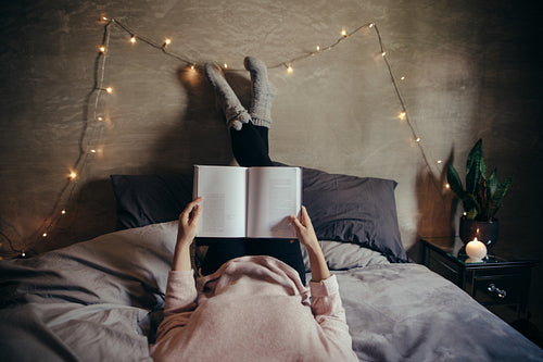 Woman lying on bed and reading book.