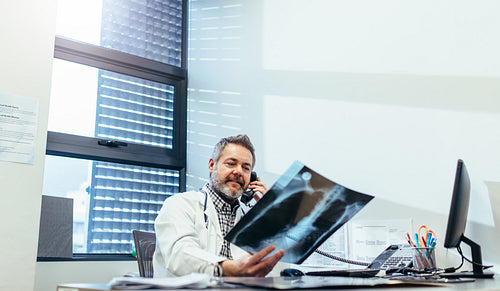 Doctor examining x-ray and talking on phone
