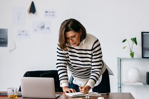 The woman captures focused writing and planning at an office desk
