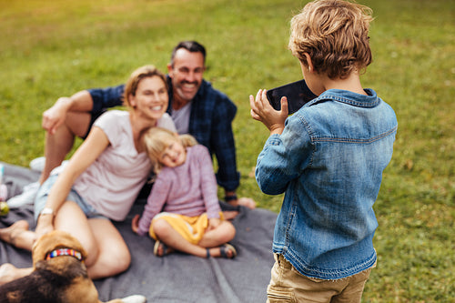 Son photographing family during picnic at park