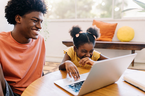 Young girl laughing while watching funny videos with her brother