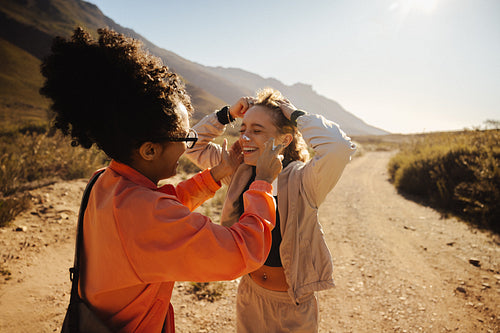 Friends sharing sunscreen on sunny trail