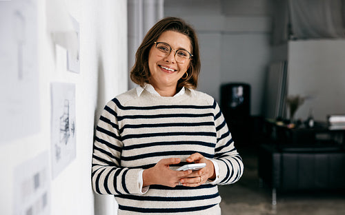 Her office scene shows the woman using a smartphone near design drawings