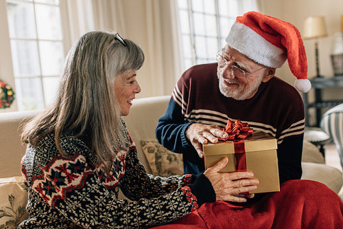 Senior couple at home exchanging christmas gifts
