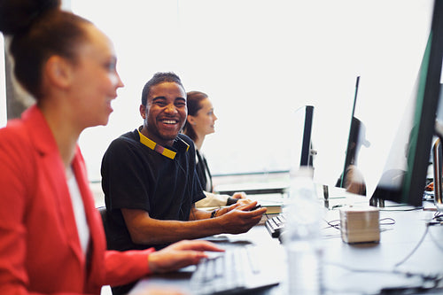 Young student in class with other students working on computers