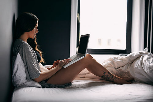 Young woman using laptop computer in bedroom