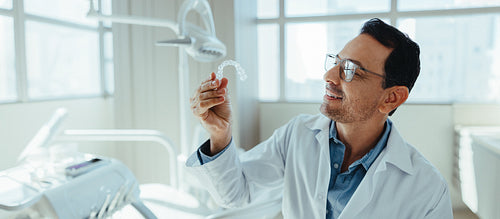 Male dentist reviewing a clear aligner in clinic for treatment care