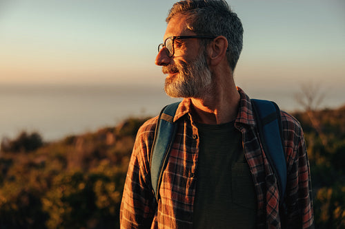 Adventurous male hiker looking away while standing on a hilltop