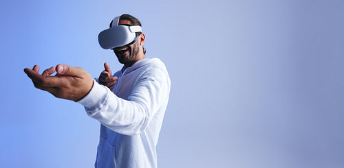 Cheerful young man shooting in a virtual reality game