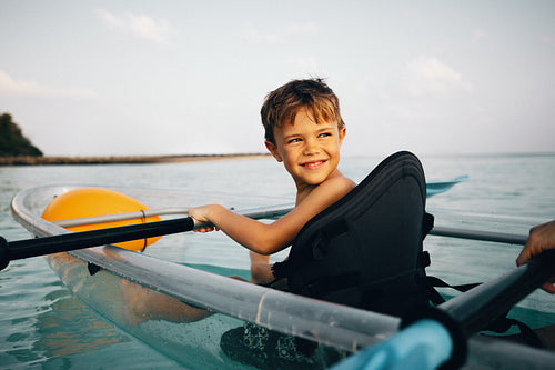 Young boy kayaking in clear waters on a sunny day